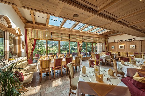 Speisesaal Ferienhotel Sonnenhof, Sonnenlicht kommt strahlt durch Wintergarten auf gedeckte Tische