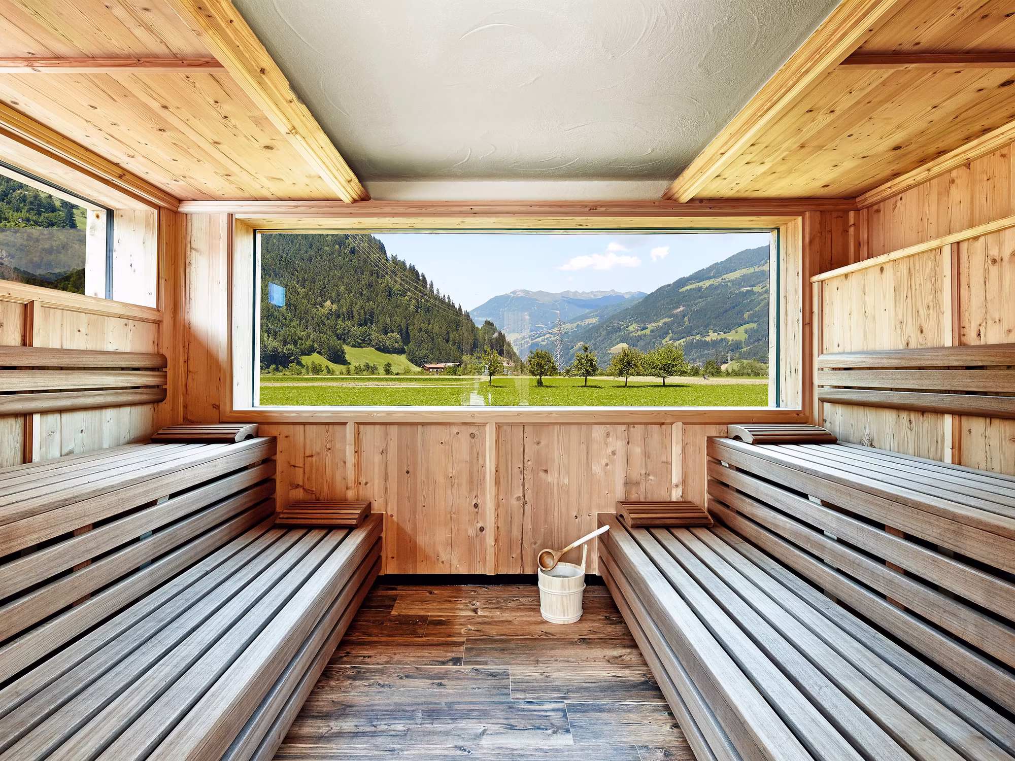 Aussensauna mit Sitzbänken und Panoramafenster Richtung talauswärts