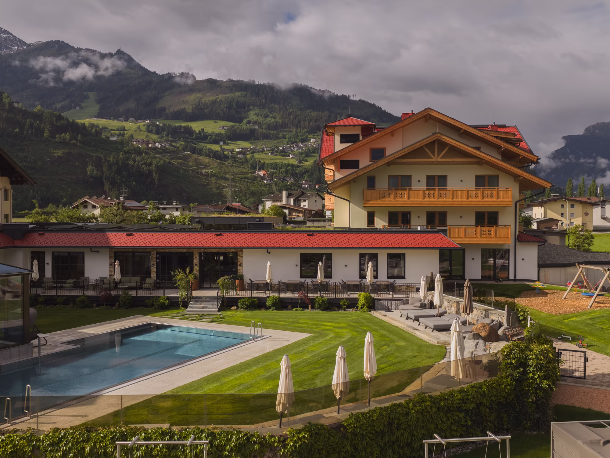 Blick auf den Garten, Terrasse und Pool mit Liegewiese © RIEDER Zillertal / GeislerStudio
