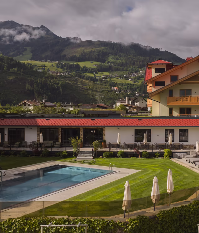 Blick auf den Garten, Terrasse und Pool mit Liegewiese © RIEDER Zillertal / GeislerStudio