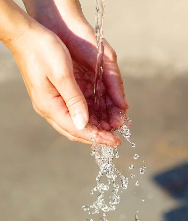 Frau hält Hände unter Wasserstrahl