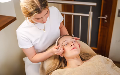 Kosmetikerin zupft die Augenbrauen einer jungen Frau