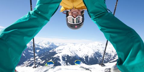 Fotografie des Bergpanoramas durch die Beine einer Skifahrerin hindurch