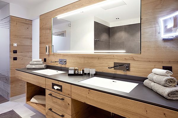 Doppelwaschbecken mit Holzunterbau und großem, hinterleuchteten Spiegel im Bad der Superior Suite des Landhauses