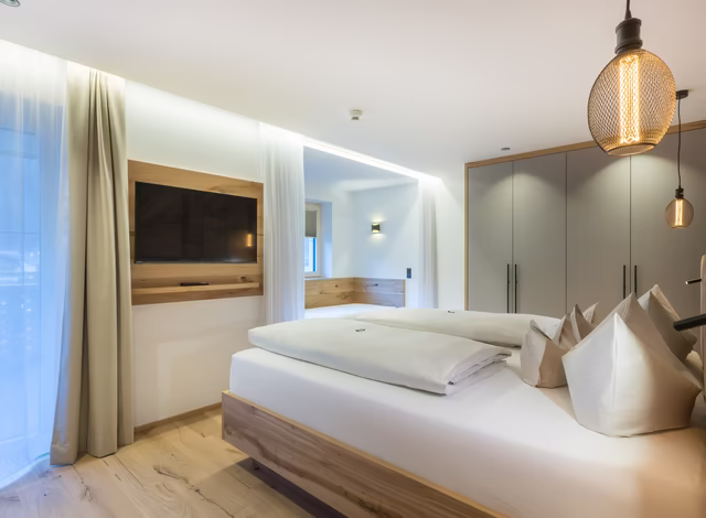 Alpin Suite Schlafzimmer mit Daybed und Balkonblick auf die Tiroler Bergwelt