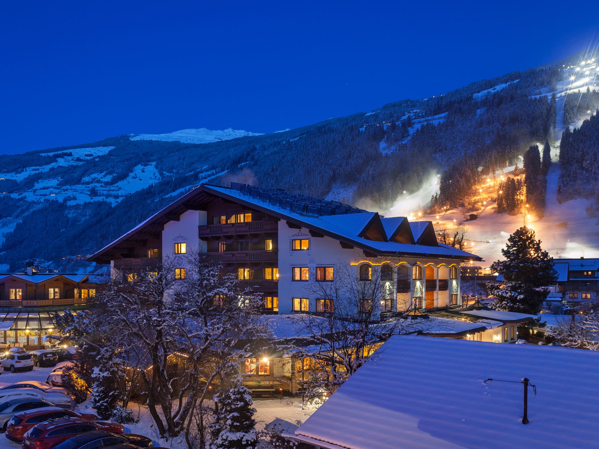 Aussenansicht des Ferienhotel Sonnenhof im Winter, abends, Blick auf beleuchtete Abfahrt Zillertal Arena