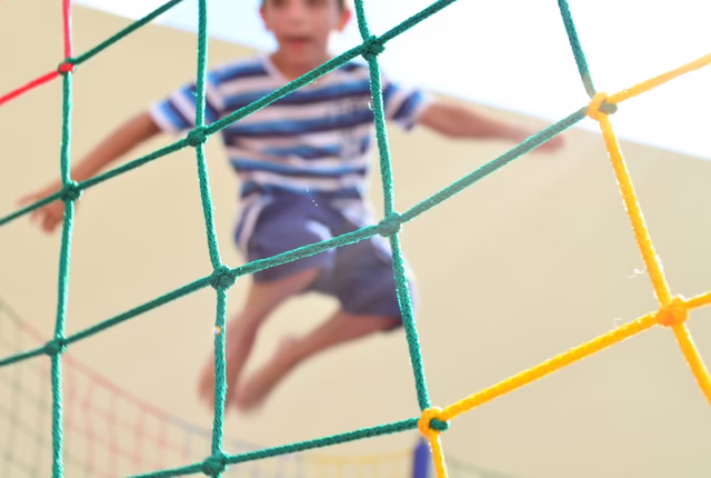Junge hüpft im Trampolin, fotografiert durch Netz