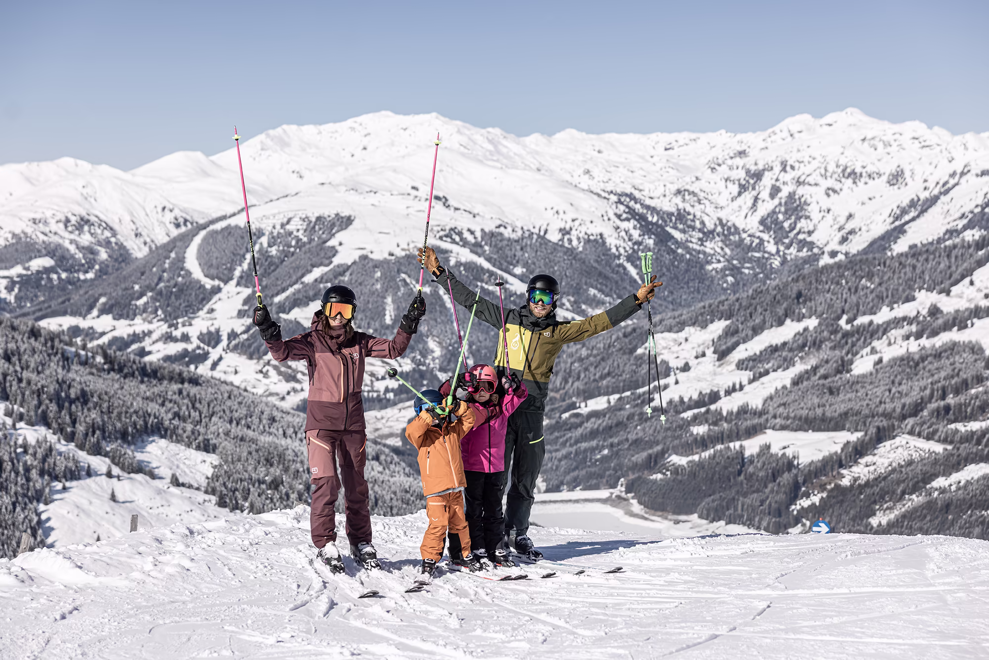 Familie posiert mit Skistöcken in der Luft für ein Foto