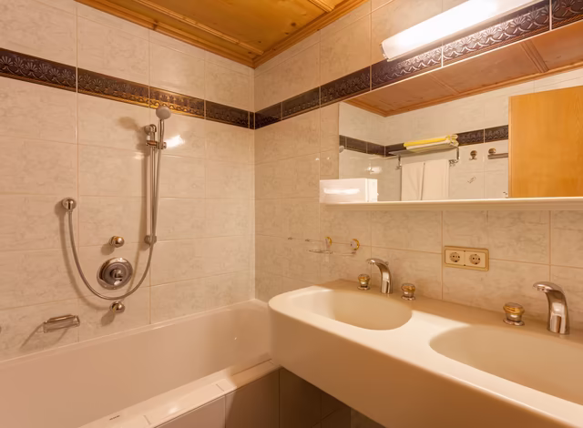 Badezimmer mit Doppelwaschbecken und Badewanne im Komfortzimmer